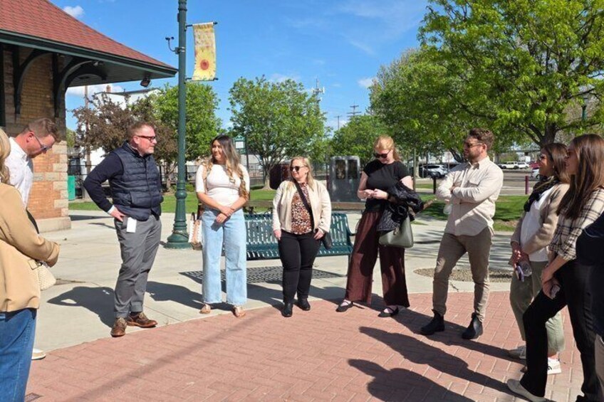 A group of people standing on a brick pathway in an outdoor setting with trees and a building in the background. 3
