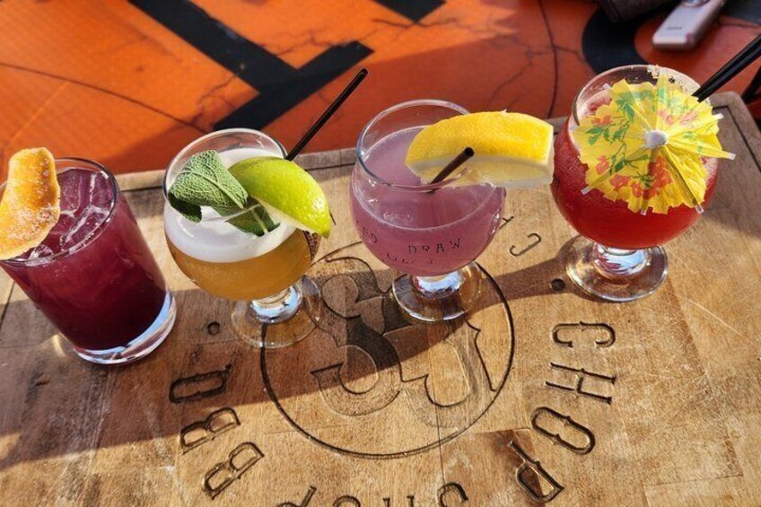 Four cocktails on a wooden table with a circular logo. 4
