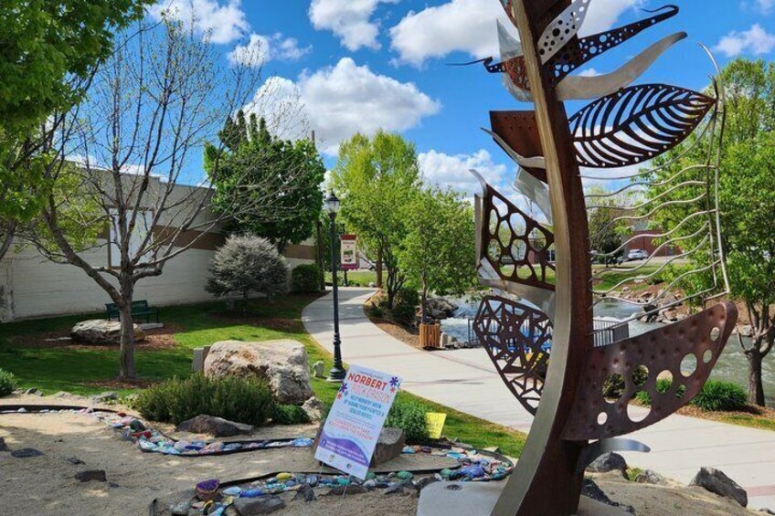 A garden with a metal sculpture, a sign, and a pathway. 1