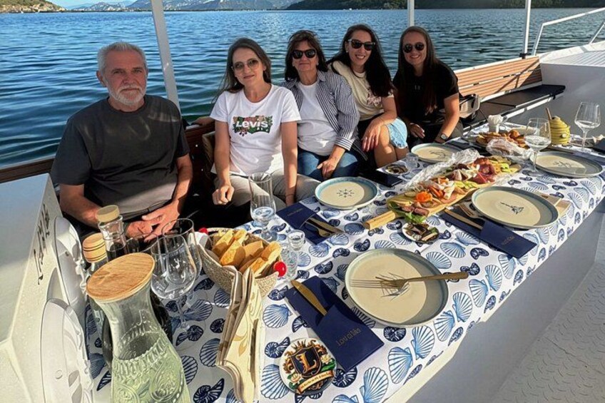 A group of people dining on a boat with a table set for a meal. 3