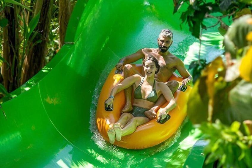 Two people sliding down a green water slide. 4