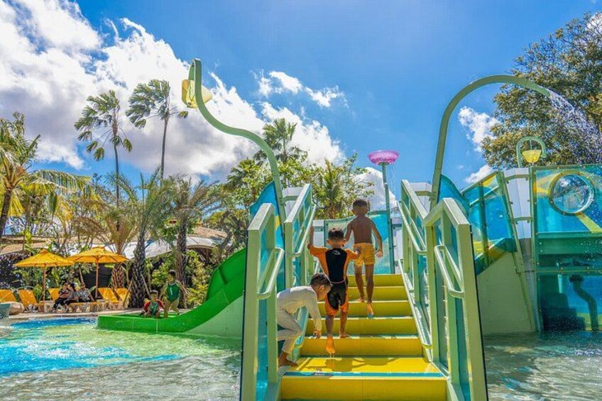 A water park with a green slide, yellow stairs, and palm trees. 5