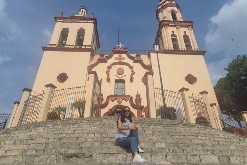 A person sitting on stone steps in front of a church with two bell towers. 1