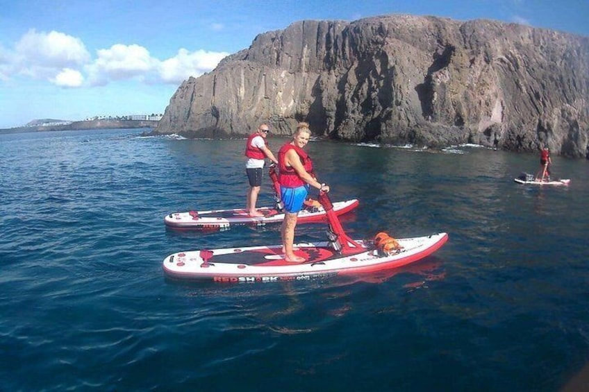 Two people on paddleboards in the ocean with a rocky cliff in the background. 5