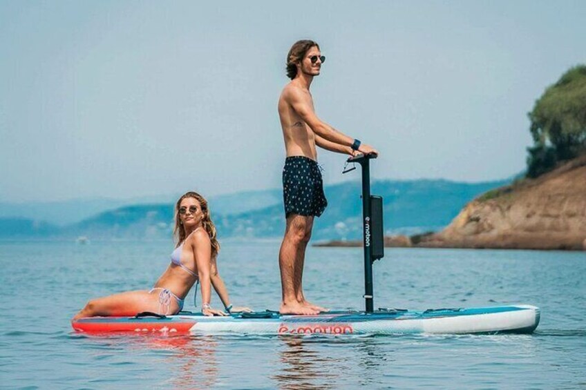 Two people on paddleboards in a body of water with a distant shoreline. 1