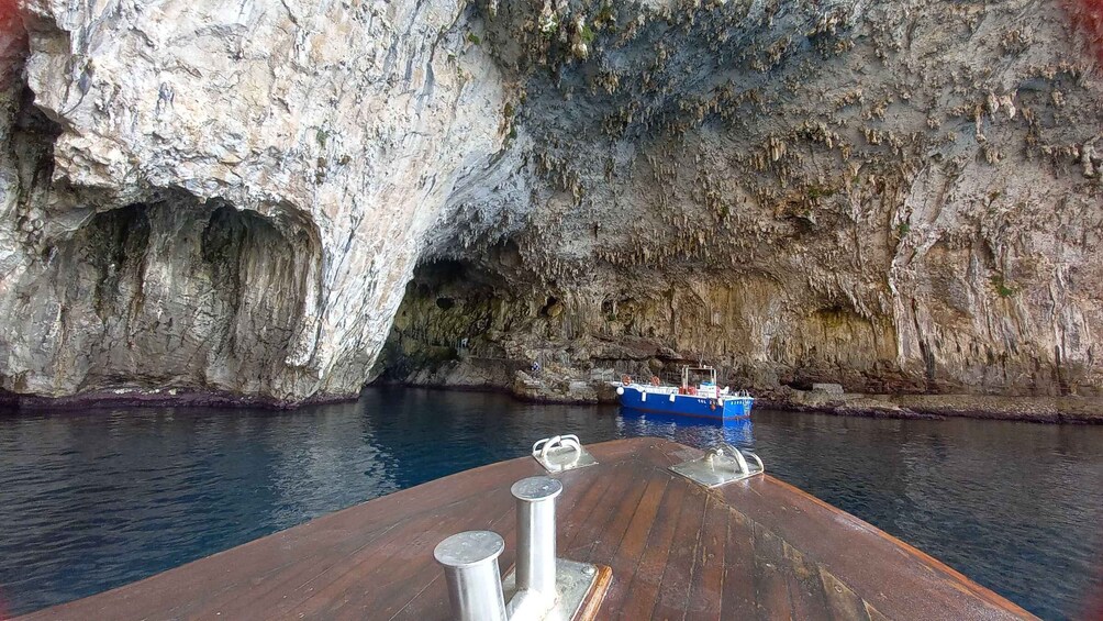 A boat docked near a rocky cliff with a cave entrance. 3