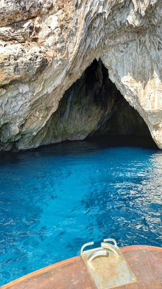 A clear blue pool with a rocky cave entrance. 2