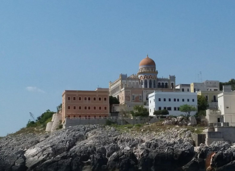 A historic building with a dome, situated on a rocky hillside with modern buildings nearby. 4