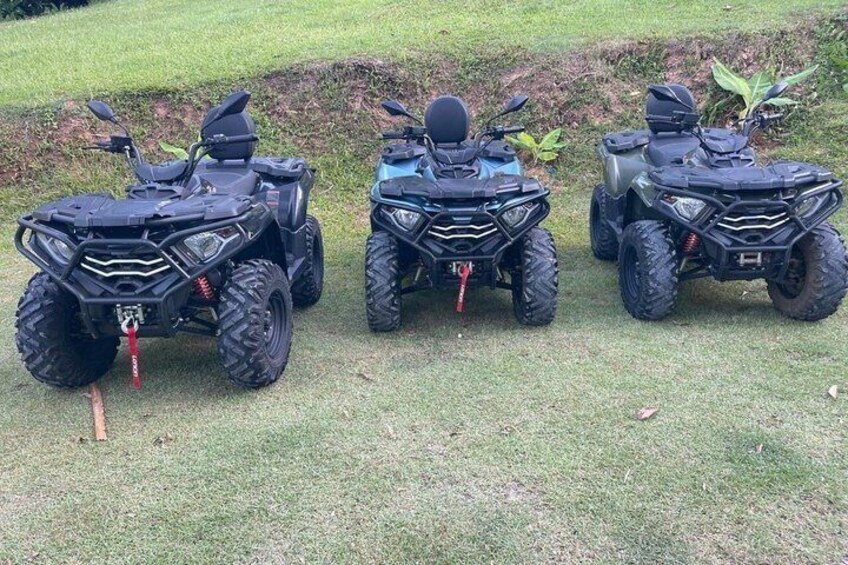 Three ATVs parked on grass with a grassy field in the background. 2