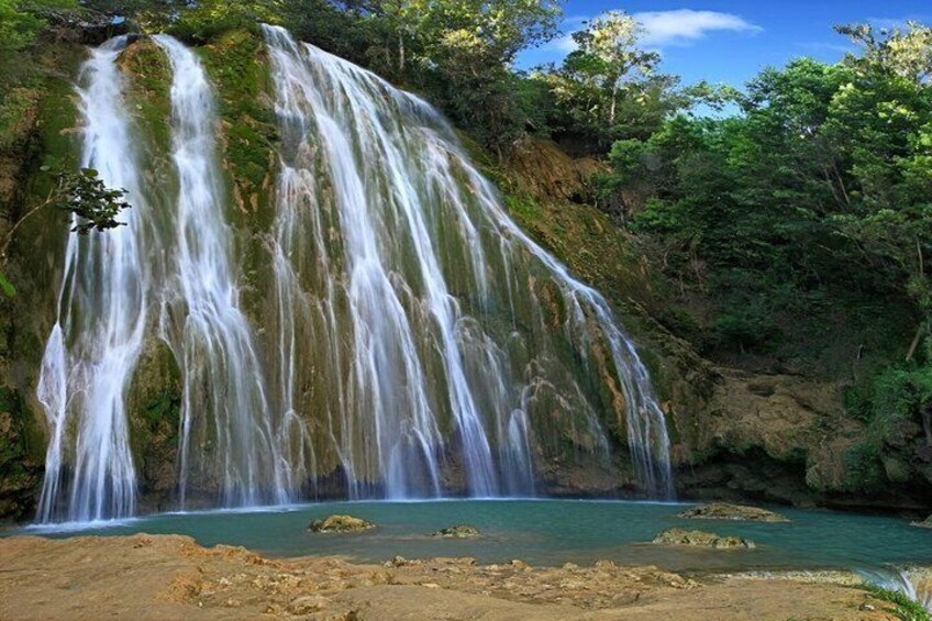 A waterfall cascading into a turquoise pool surrounded by lush greenery. 1