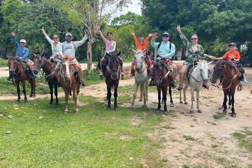 A group of people on horseback in a grassy area with trees in the background. 4
