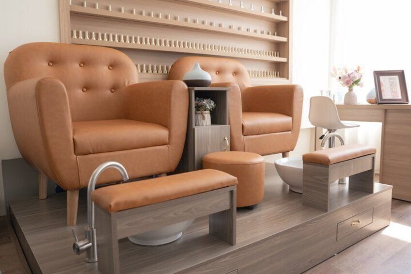 A modern living room with a large brown leather sofa, a matching ottoman, a wooden coffee table, and a side table with a vase and picture frame. 2