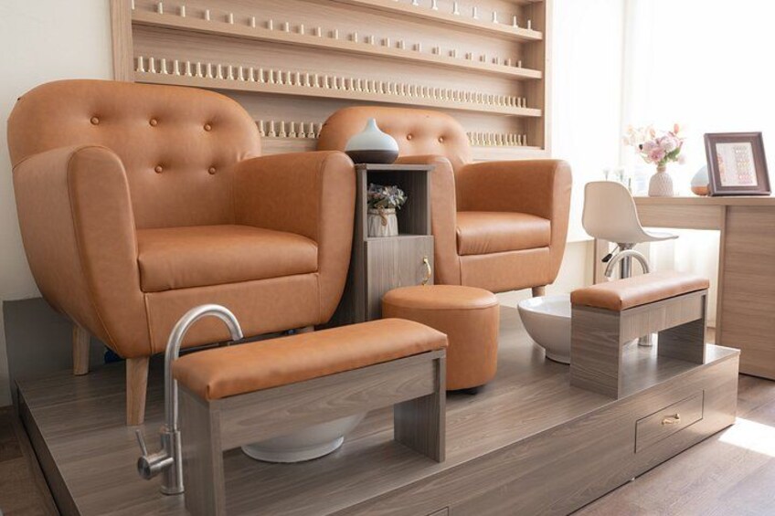 A modern living room with a large tan sofa, a matching ottoman, a coffee table, and a side table with a vase and picture frame. 2