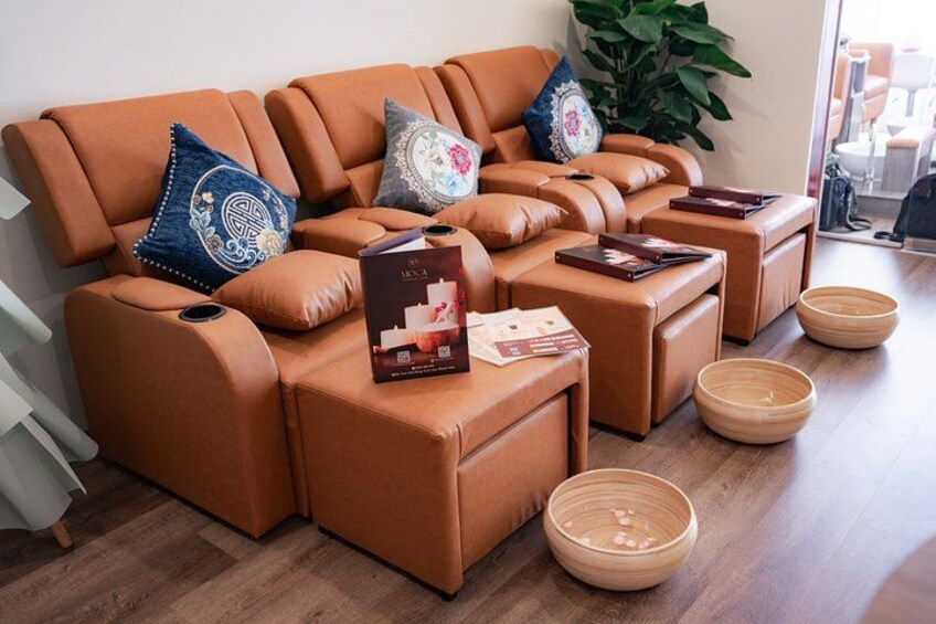 A brown leather sofa with cushions, a coffee table, and a small side table with a book and magazines. 4