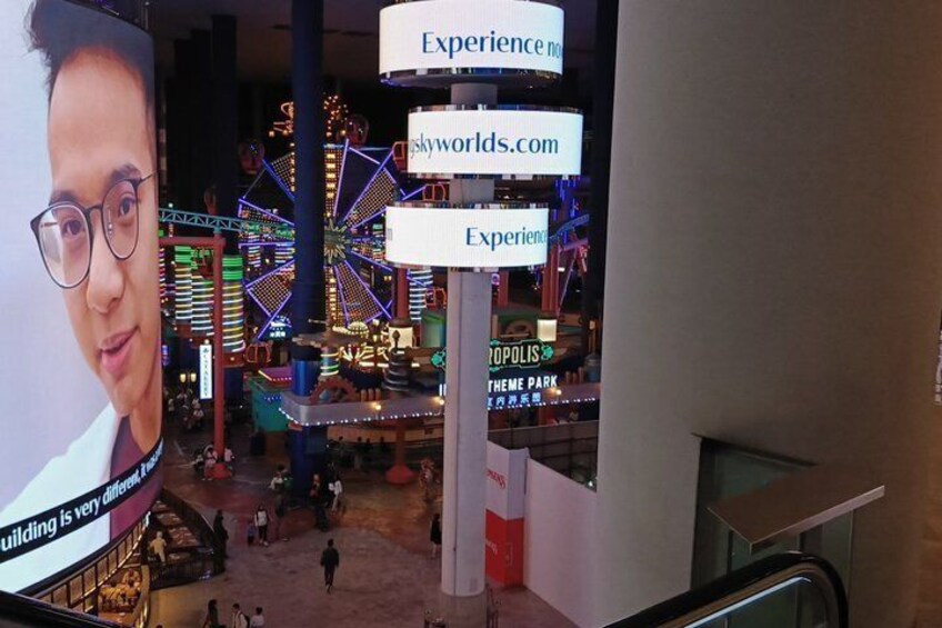 An indoor amusement park with a Ferris wheel, a large sign for 'Experience,' and a banner advertising 'skyworlds.com.' 4