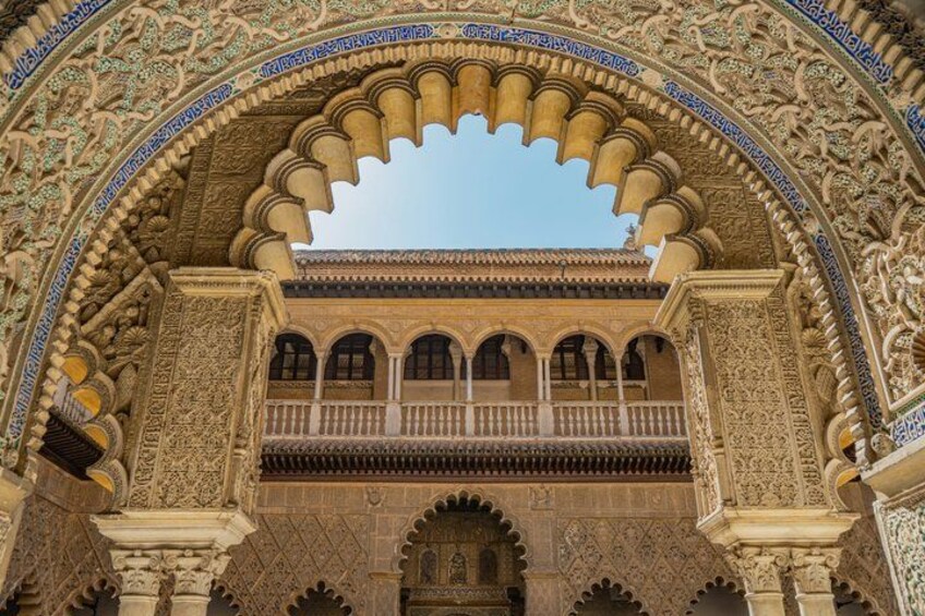 An ornate archway with intricate carvings and a balcony overlooking a courtyard. 1