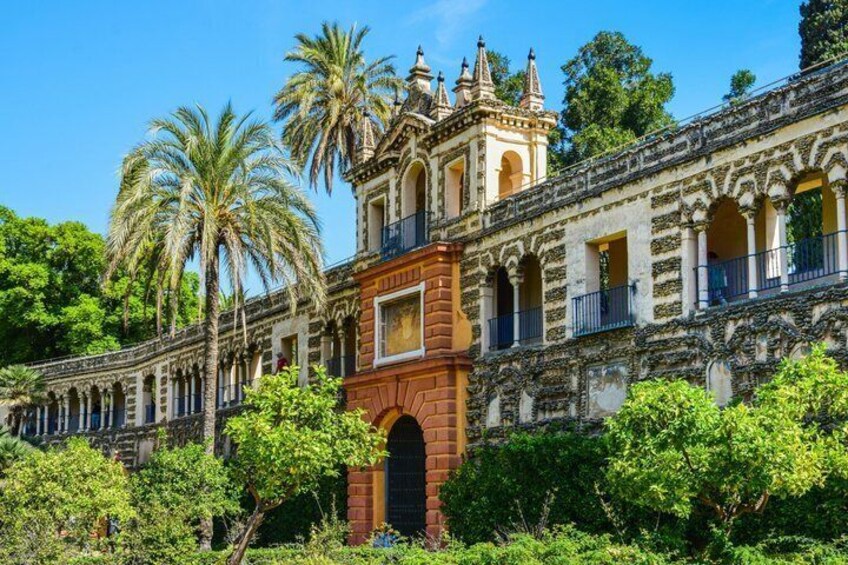 A historic building with ornate architecture, palm trees, and lush greenery. 1