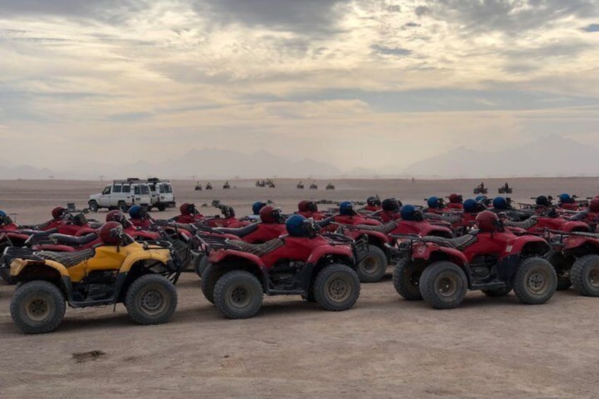 A group of ATVs parked in a desert landscape with a cloudy sky. 1