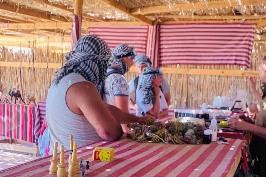 A group of people playing chess at a table with a red and white striped tablecloth. 3