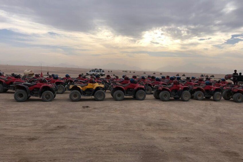 A desert landscape with rows of ATVs parked on the sand. 4