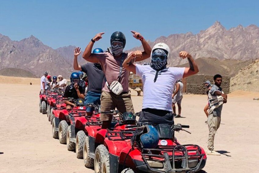 A group of people on ATVs in a desert landscape with mountains in the background. 4