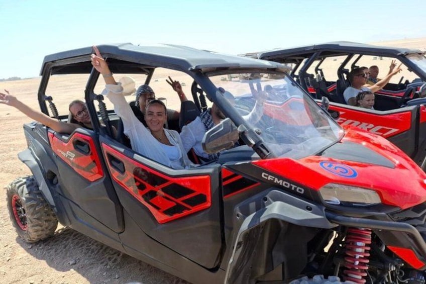 A group of people in a red and black off-road vehicle. 5