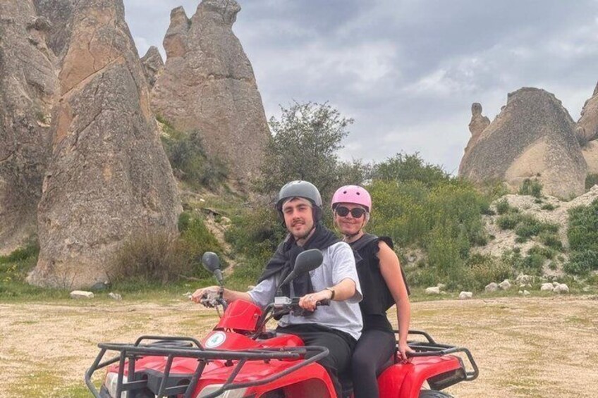 Two people on a red ATV in a rocky outdoor setting. 5