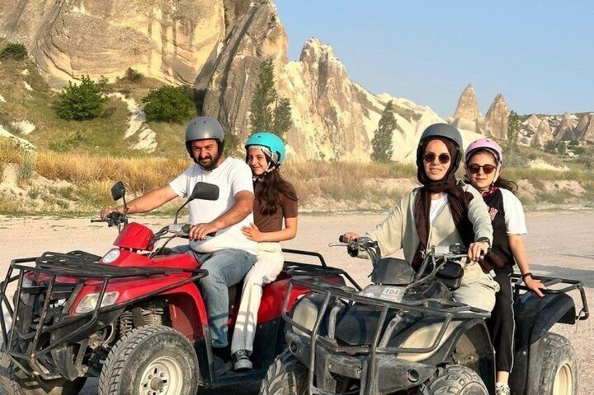 Four people on ATVs in a rocky, desert-like landscape with large rock formations. 2