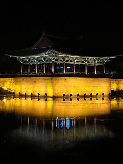 A traditional Korean palace at night, reflected in a calm body of water. 1