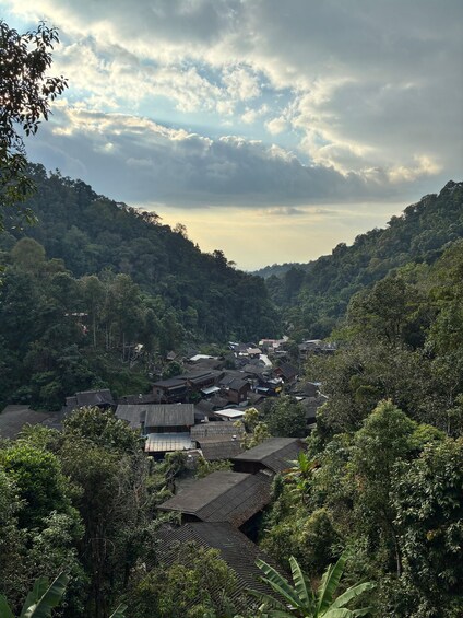 A village nestled in a valley with traditional houses and dense forested hills. 3