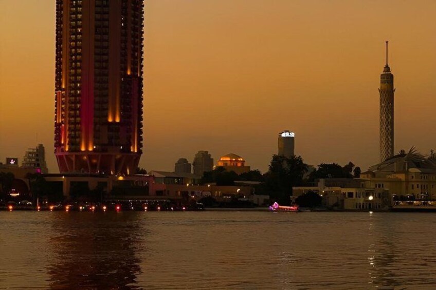 A city skyline at dusk with illuminated buildings and a river in the foreground. 3