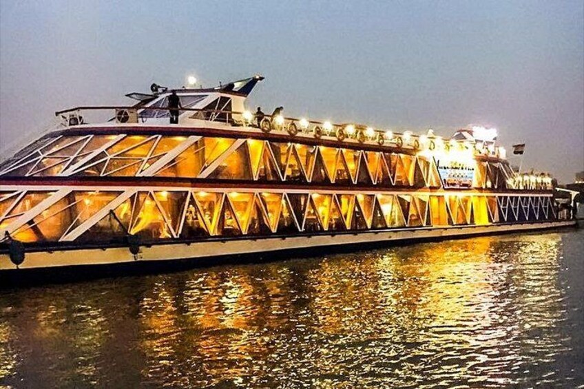 Un gran barco fluvial iluminado con un diseño triangular distintivo en las ventanas y un techo plano. 1