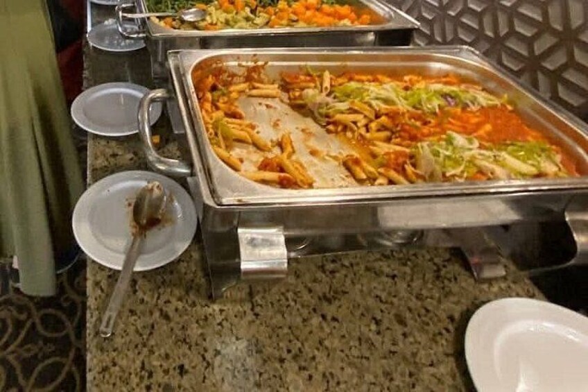 Un bufé con platos de pasta, ensalada y otras opciones de comida. 5