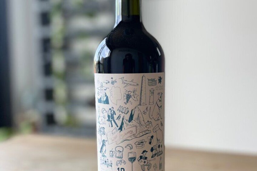 A wine bottle with a label featuring illustrations of people and various objects. 2