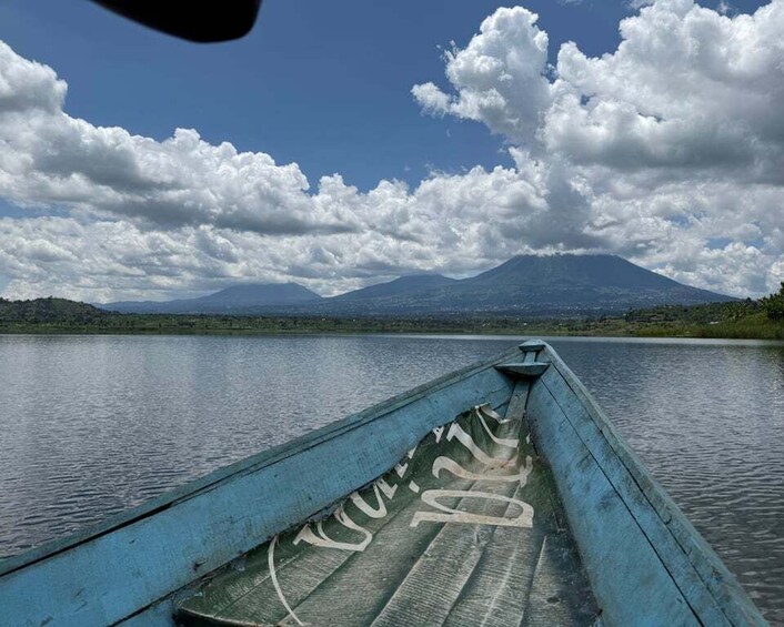 A wooden boat on calm water with a mountain in the background. 1