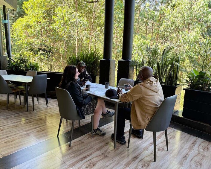 A group of people seated at a table in an outdoor cafe with wooden flooring and potted plants. 5