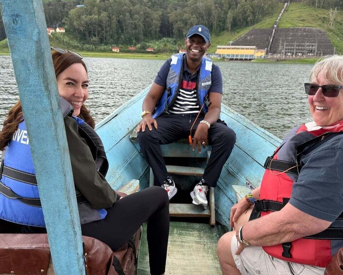 Three people on a boat with a lake and hills in the background. 3