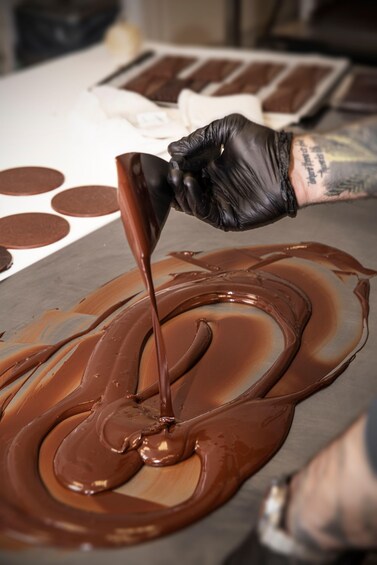 A person pouring chocolate on a flat surface. 2