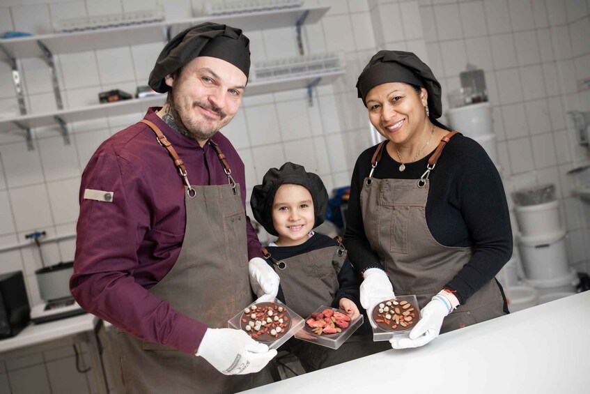Three people in a kitchen holding trays of food. 3