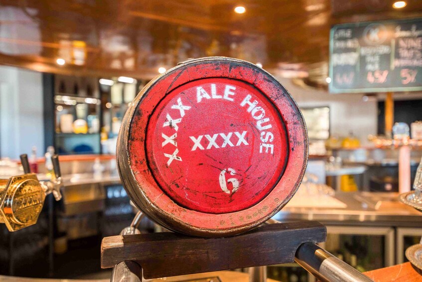 A red beer tap with 'XXX ALE HOUSE' and 'XXXX' on it, set in a bar environment. 2