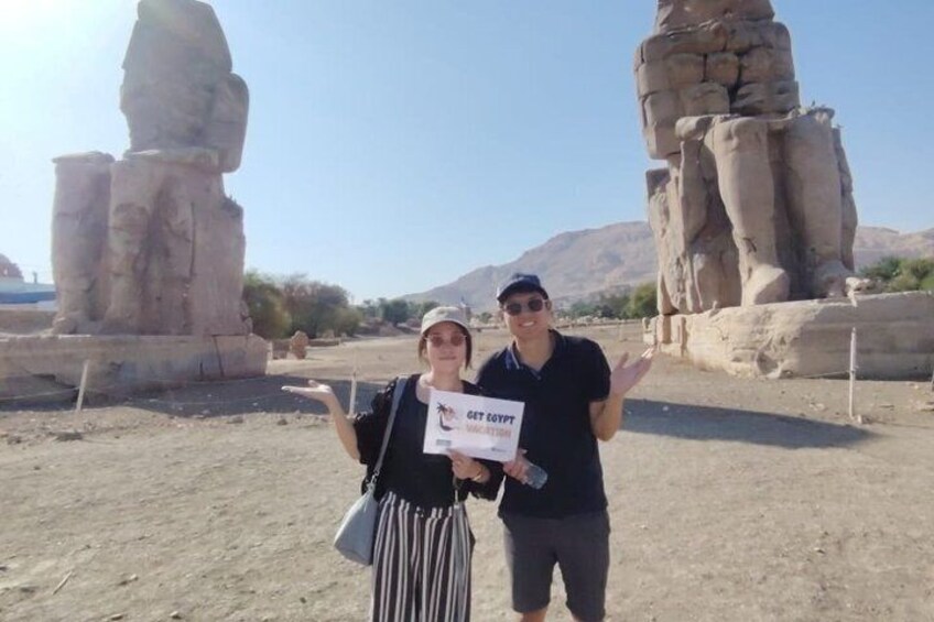 Two people standing in front of ancient rock formations. 3