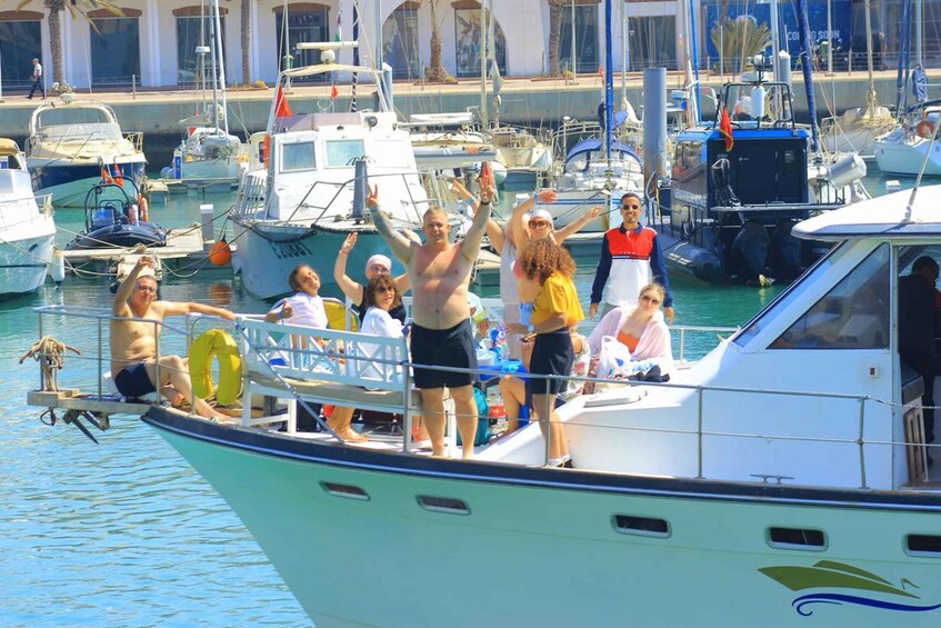 A group of people on a boat in a marina with multiple other boats docked. 1