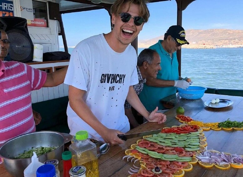 A person preparing food on a boat with various vegetables and condiments. 3
