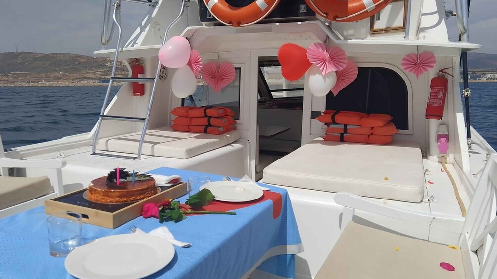 A boat deck with a birthday setup including a cake, balloons, and decorations. 2