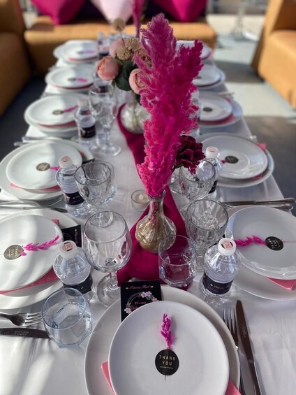 A table set with white plates, pink accents, and clear glassware. 4
