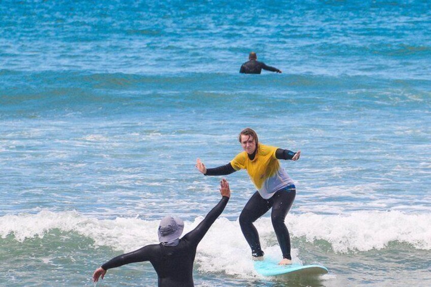 A person surfing on a wave with another person in the water. 1