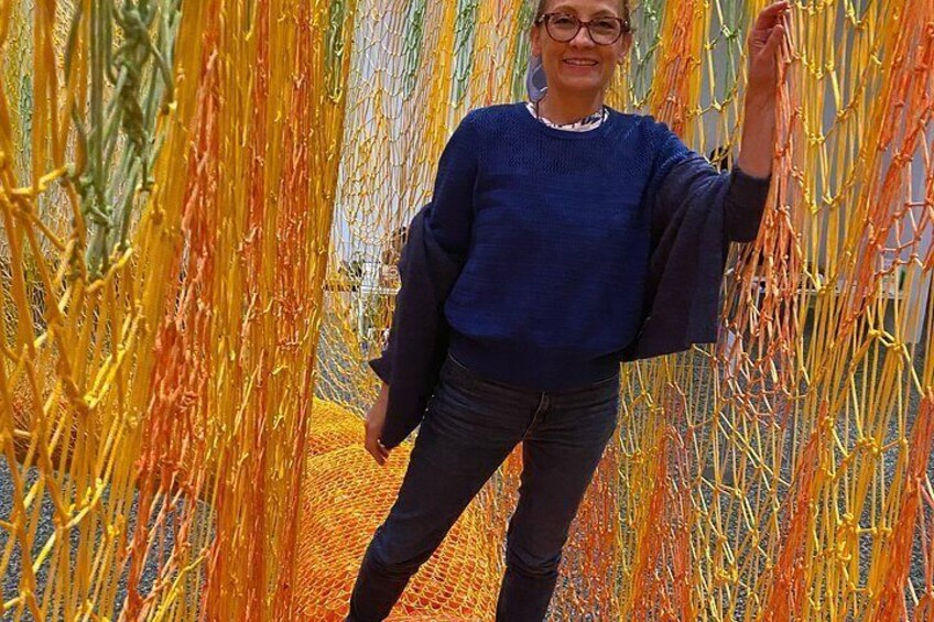 A person standing in front of a colorful, net-like structure. 2