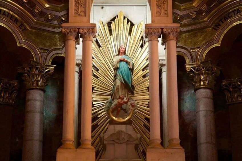 A statue of a religious figure surrounded by golden rays, set within an ornate architectural structure with columns. 4
