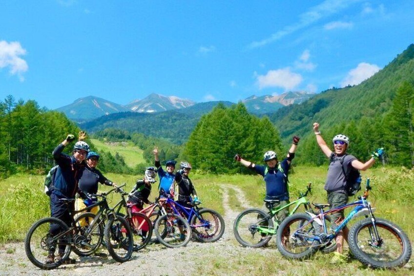 A group of cyclists on a mountain trail with a scenic view of mountains and trees. 3