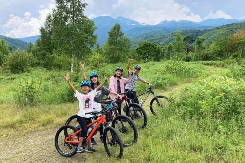 A group of cyclists on a trail with mountains in the background. 1
